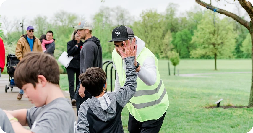 5k race day volunteer giving high five to runner