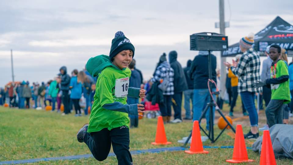 boy running happily beside running coach