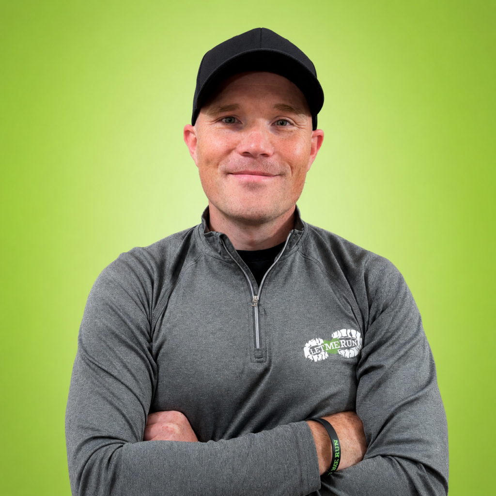 Portrait of a smiling man in a gray quarter-zip jacket and black cap, arms crossed, bright lime green background.
