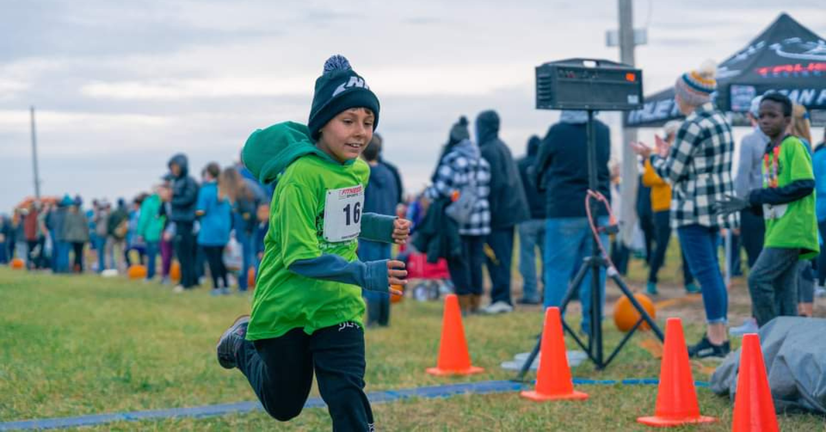 boy running past the finish line after 5k