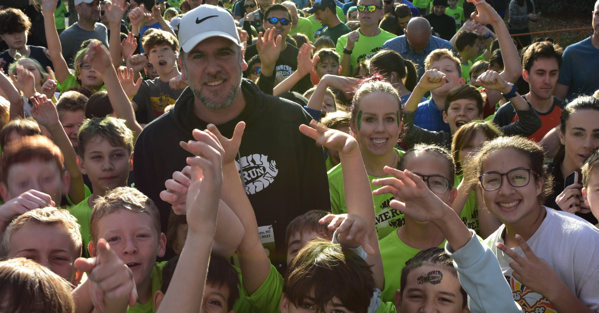 head coach posing for photo with running group